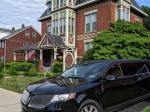 Red brick mansion with black limousine in the driveway